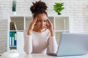 Woman have a chronic headache, touching temples to relieve pain during working on laptop
